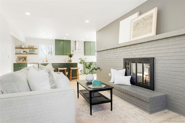 living room with recessed lighting, a brick fireplace, and light wood finished floors