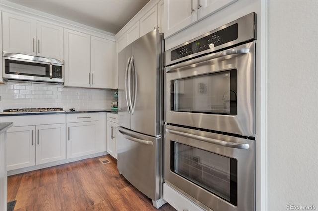 kitchen with stainless steel appliances, white cabinetry, tasteful backsplash, and dark hardwood / wood-style flooring