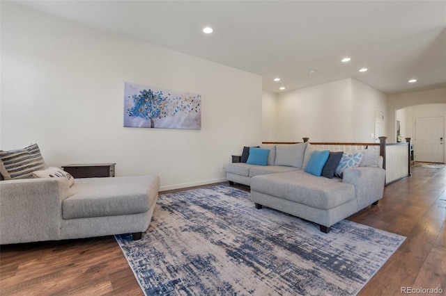 living area featuring arched walkways, baseboards, wood finished floors, and recessed lighting