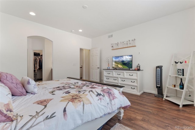 bedroom with arched walkways, recessed lighting, visible vents, a spacious closet, and dark wood-type flooring