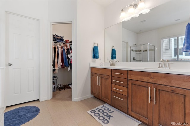 full bathroom featuring a sink, visible vents, a shower stall, double vanity, and a walk in closet