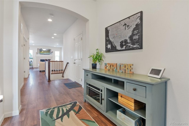 corridor with baseboards, arched walkways, dark wood finished floors, and recessed lighting