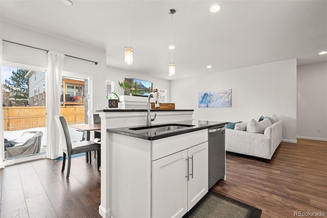 kitchen featuring dark countertops, dark wood finished floors, a sink, and stainless steel dishwasher