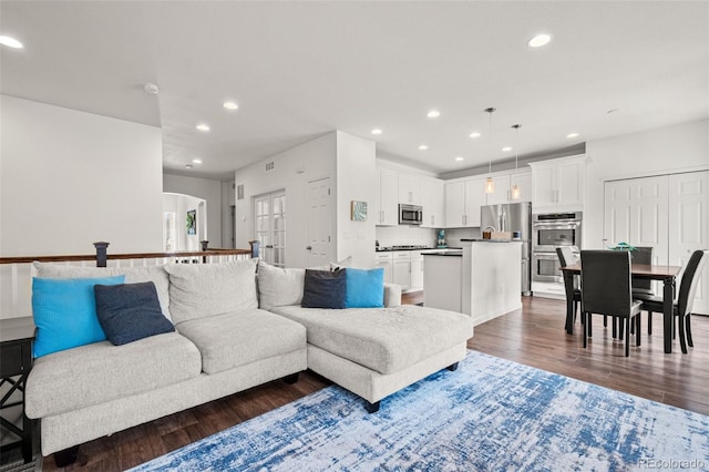 living area with recessed lighting, dark wood-style flooring, and arched walkways