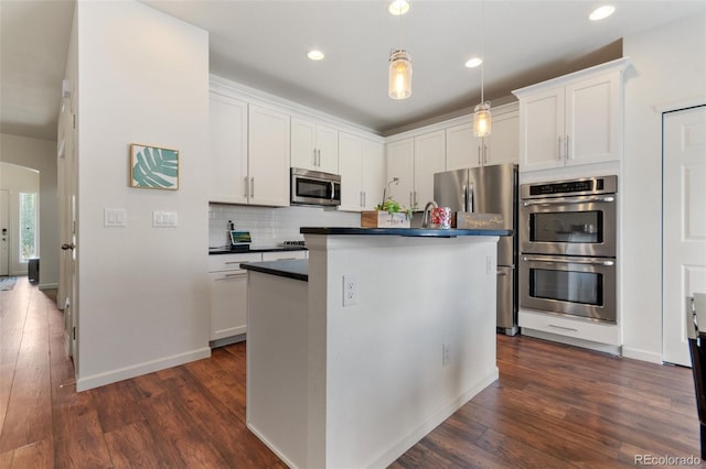 kitchen featuring stainless steel appliances, dark wood-type flooring, dark countertops, and white cabinets