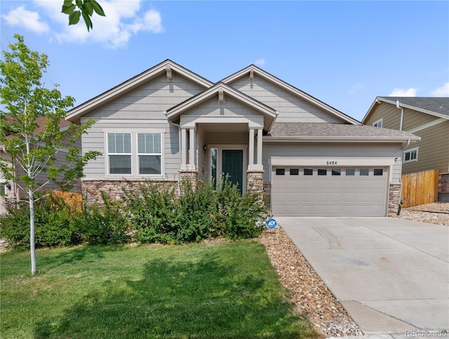 craftsman-style home with a garage, concrete driveway, stone siding, and a front yard