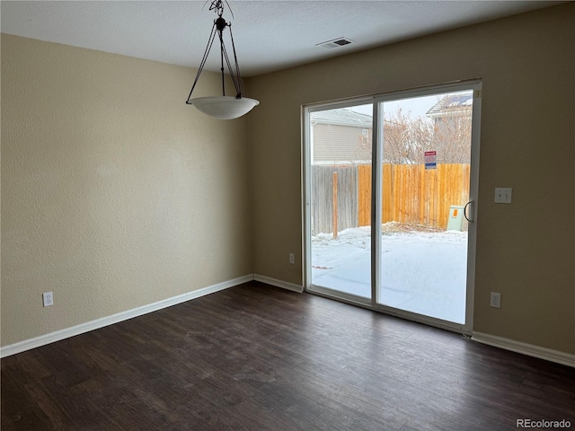 unfurnished room featuring dark wood-style floors, visible vents, and baseboards