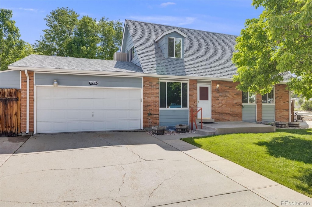 12218 Monroe Dr, Thornton, CO 80241 - cape cod home featuring an attached garage, driveway, brick siding, and a shingled roof