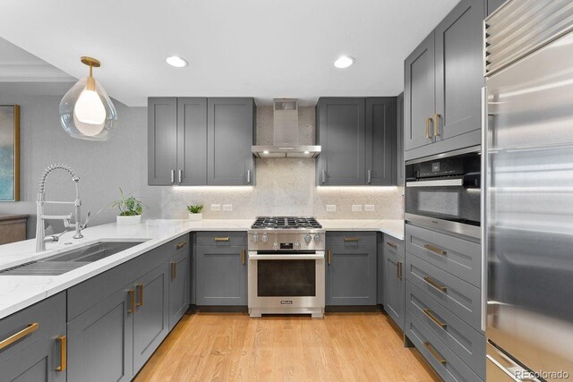 1590 Little Raven St Unit 408, Denver, CO 80202 - kitchen with light wood finished floors, a sink, high end appliances, wall chimney range hood, and gray cabinetry