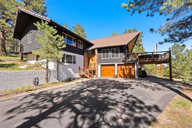2976 Hiwan Dr, Evergreen, CO 80439 - view of front of house featuring driveway, a tiled roof, a deck, and a garage
