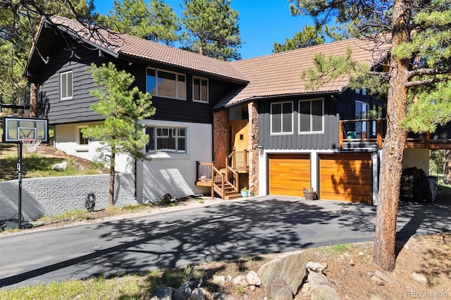 2976 Hiwan Dr, Evergreen, CO 80439 - view of front of house featuring a tile roof, asphalt driveway, a garage, stone siding, and board and batten siding