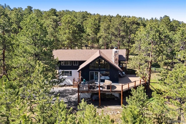 2976 Hiwan Dr, Evergreen, CO 80439 - rear view of property with a wooden deck, a wooded view, a tiled roof, and a chimney