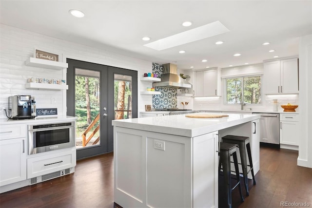 2976 Hiwan Dr, Evergreen, CO 80439 - kitchen with stainless steel appliances, wall chimney range hood, open shelves, a skylight, and tasteful backsplash