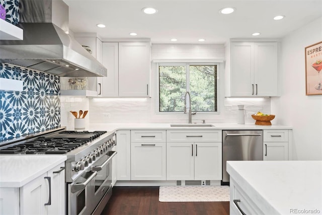 2976 Hiwan Dr, Evergreen, CO 80439 - kitchen featuring appliances with stainless steel finishes, wall chimney exhaust hood, a sink, light countertops, and dark wood-type flooring