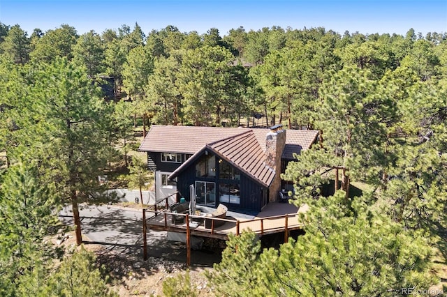 2976 Hiwan Dr, Evergreen, CO 80439 - back of house featuring board and batten siding, a deck, a forest view, and a chimney