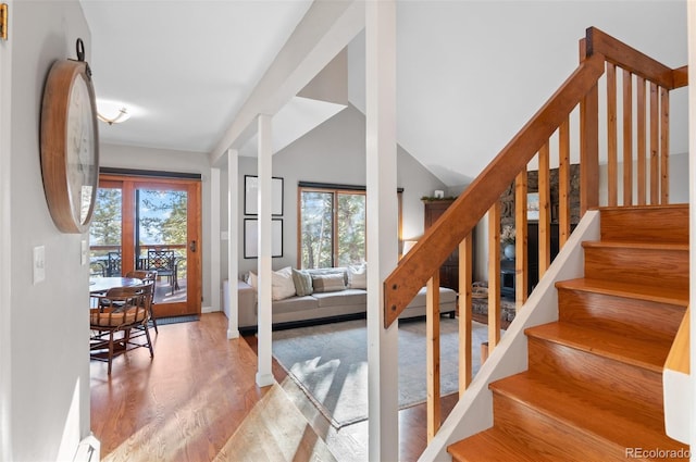 staircase with lofted ceiling, wood finished floors, and a wealth of natural light