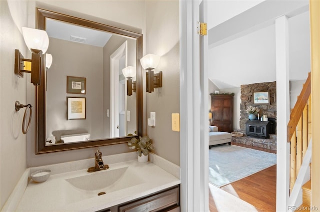 bathroom featuring a wood stove, visible vents, wood finished floors, and vanity