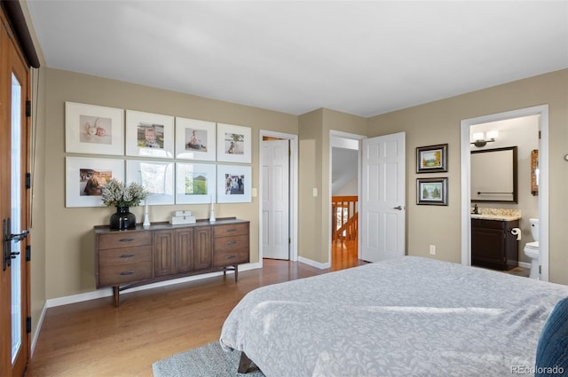 bedroom featuring baseboards, wood finished floors, and ensuite bathroom