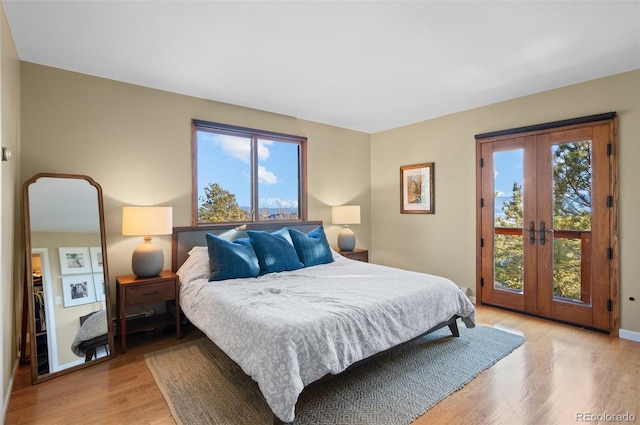 bedroom featuring light wood-style floors, access to outside, multiple windows, and baseboards