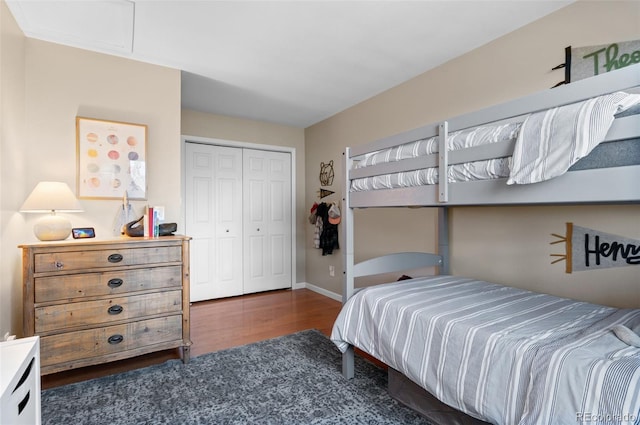 bedroom with dark wood-style flooring, a closet, and baseboards