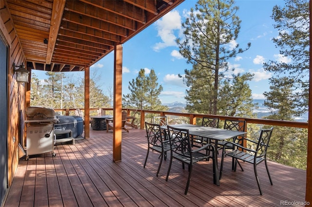 wooden deck with outdoor dining area and grilling area