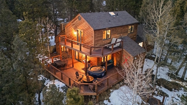 snow covered property featuring a deck, a shingled roof, and a balcony