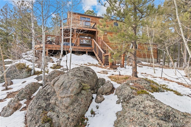 snow covered rear of property with stairway and a deck