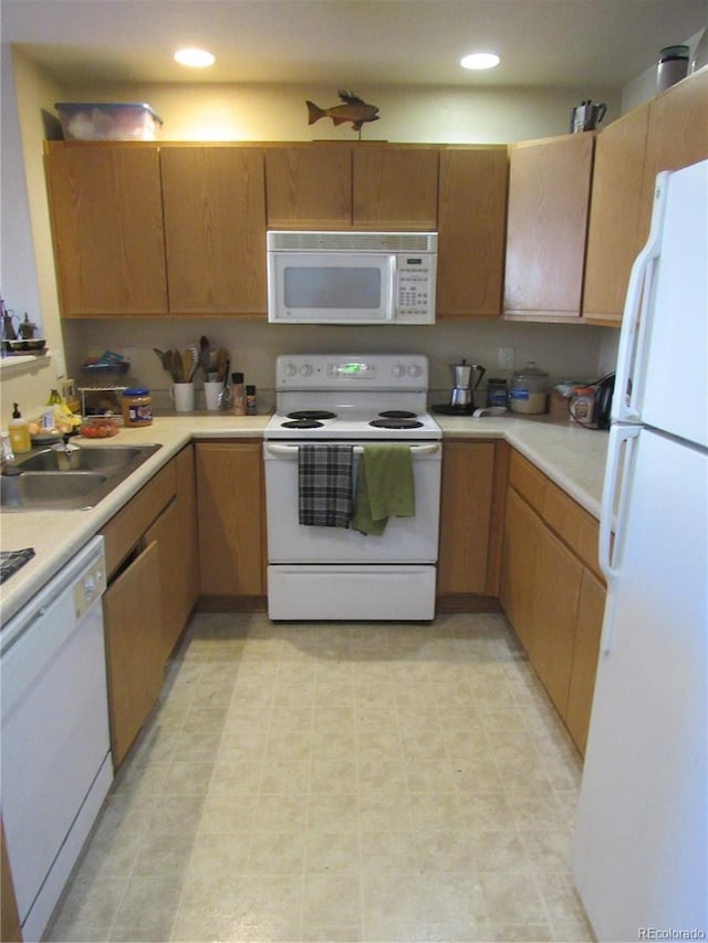 kitchen with light floors, recessed lighting, light countertops, a sink, and white appliances