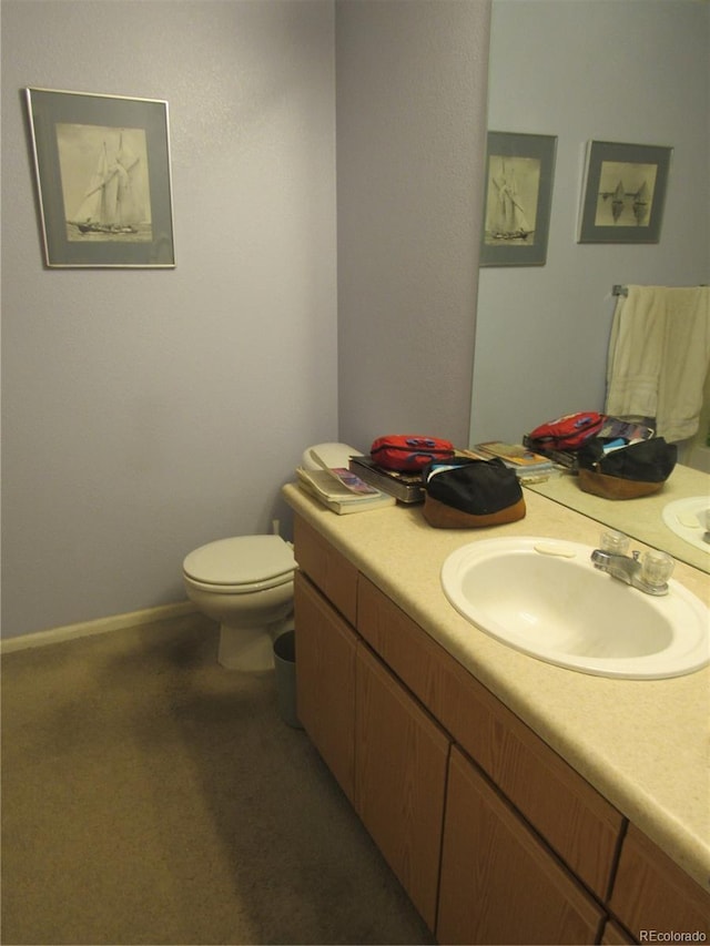 bathroom with toilet, baseboards, and vanity