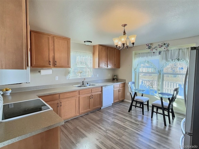 kitchen featuring dishwasher, a chandelier, hanging light fixtures, stainless steel fridge, and sink