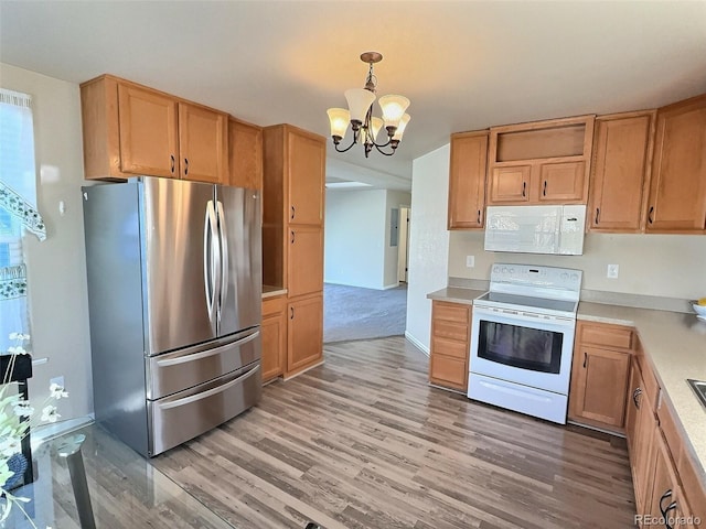 kitchen featuring white appliances, hanging light fixtures, light hardwood / wood-style flooring, and an inviting chandelier