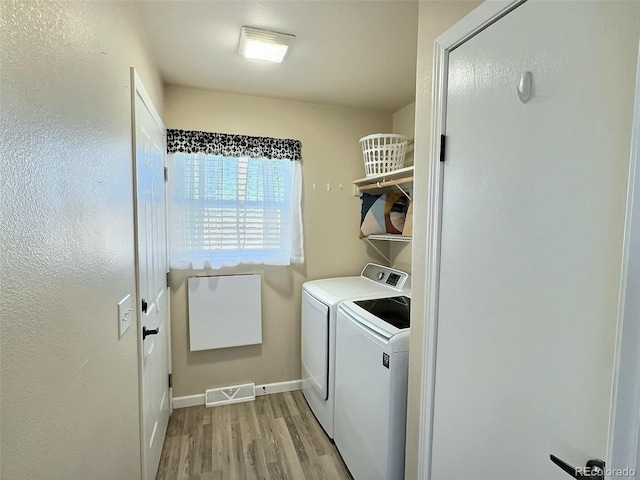 laundry area featuring washing machine and dryer and light hardwood / wood-style flooring