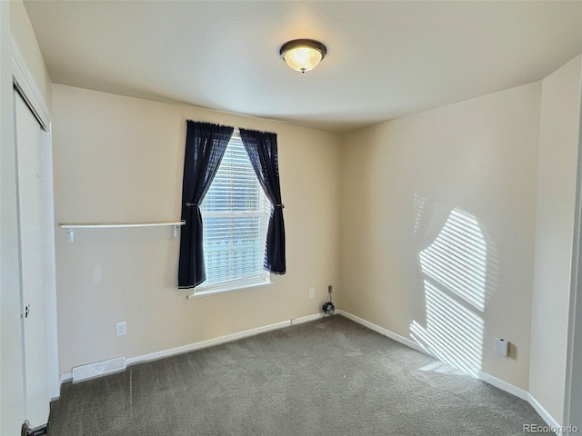 unfurnished room featuring dark carpet