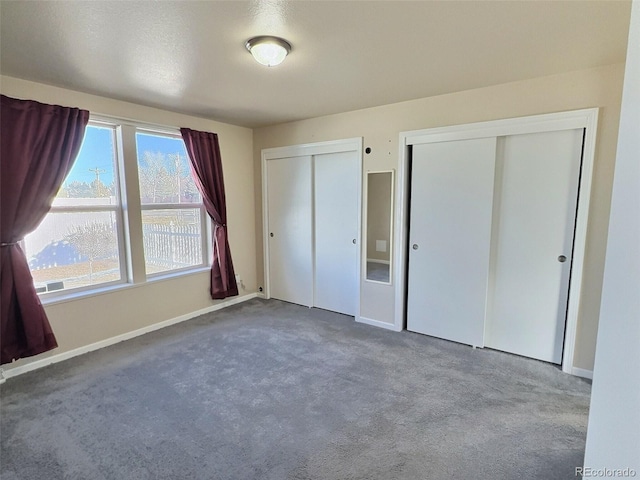 unfurnished bedroom with two closets and carpet