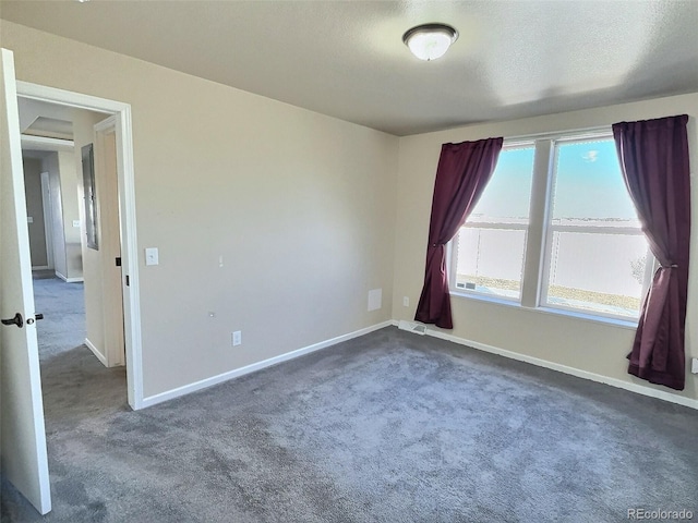 unfurnished room with a textured ceiling and dark colored carpet