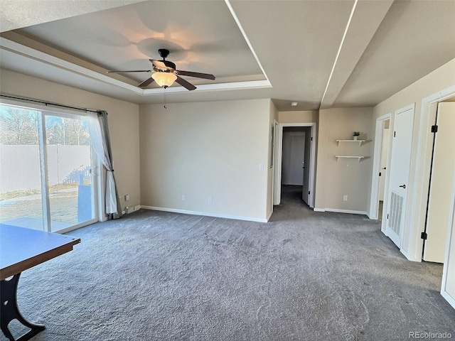 carpeted empty room with ceiling fan and a tray ceiling