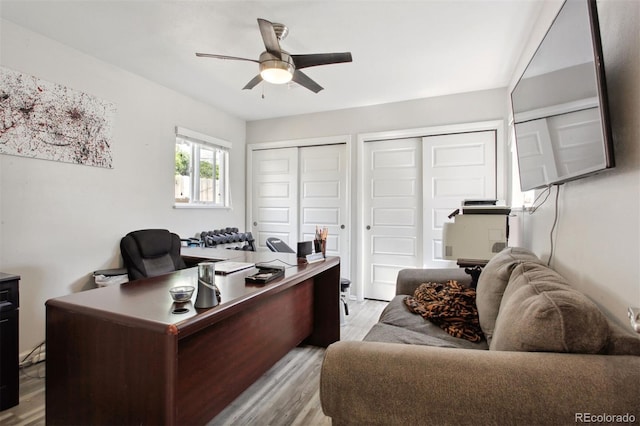 office with light wood-type flooring and ceiling fan