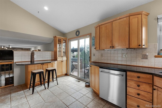 kitchen featuring tasteful backsplash, light tile patterned floors, a breakfast bar area, dishwasher, and lofted ceiling