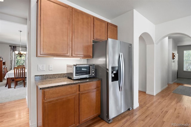 6471 S Ider St, Aurora, CO 80016 - kitchen featuring stainless steel refrigerator with ice dispenser, arched walkways, brown cabinets, and light wood-style flooring