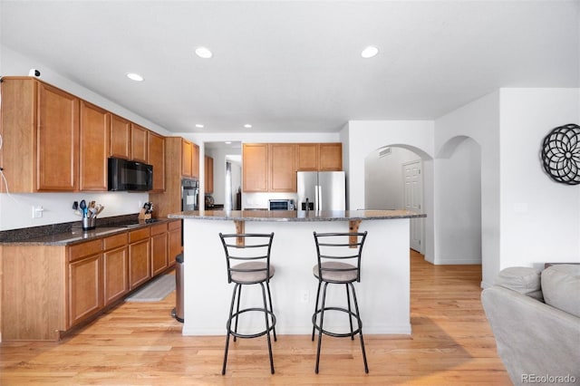 6471 S Ider St, Aurora, CO 80016 - kitchen featuring appliances with stainless steel finishes, arched walkways, a breakfast bar, a kitchen island, and recessed lighting