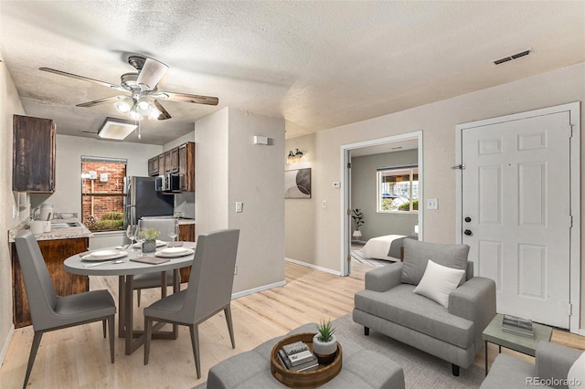 dining room featuring sink, a textured ceiling, ceiling fan, and light hardwood / wood-style flooring