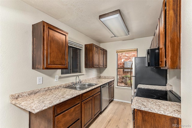 kitchen featuring a textured ceiling, stainless steel appliances, light hardwood / wood-style floors, and sink