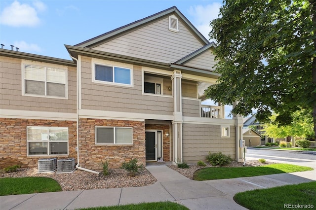 townhome / multi-family property with central AC, a balcony, and stone siding