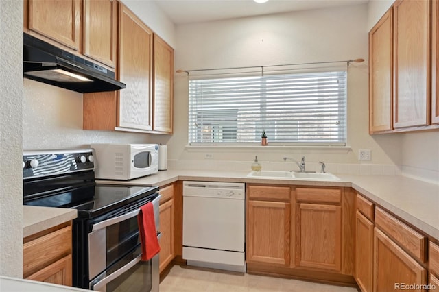 kitchen with white appliances, under cabinet range hood, a sink, and light countertops
