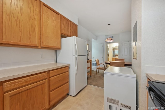 kitchen featuring freestanding refrigerator, stove, light countertops, white fridge, and pendant lighting