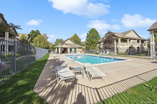 community pool featuring fence, a patio, a residential view, and an outbuilding