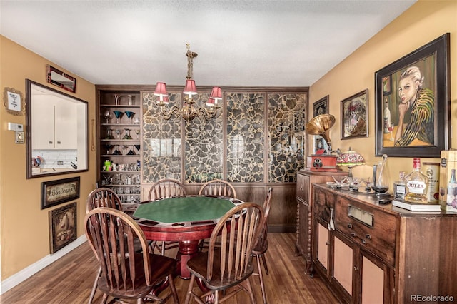 dining room featuring built in features, dark wood-type flooring, and an inviting chandelier