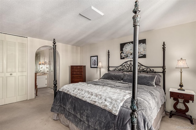 bedroom featuring light colored carpet, a textured ceiling, and a closet