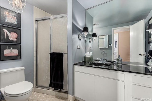 bathroom featuring vanity, toilet, an inviting chandelier, and a shower with door