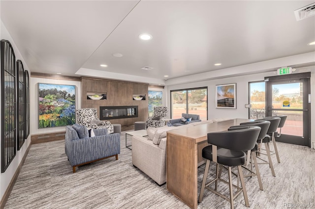 living room featuring a raised ceiling, a large fireplace, and a wealth of natural light